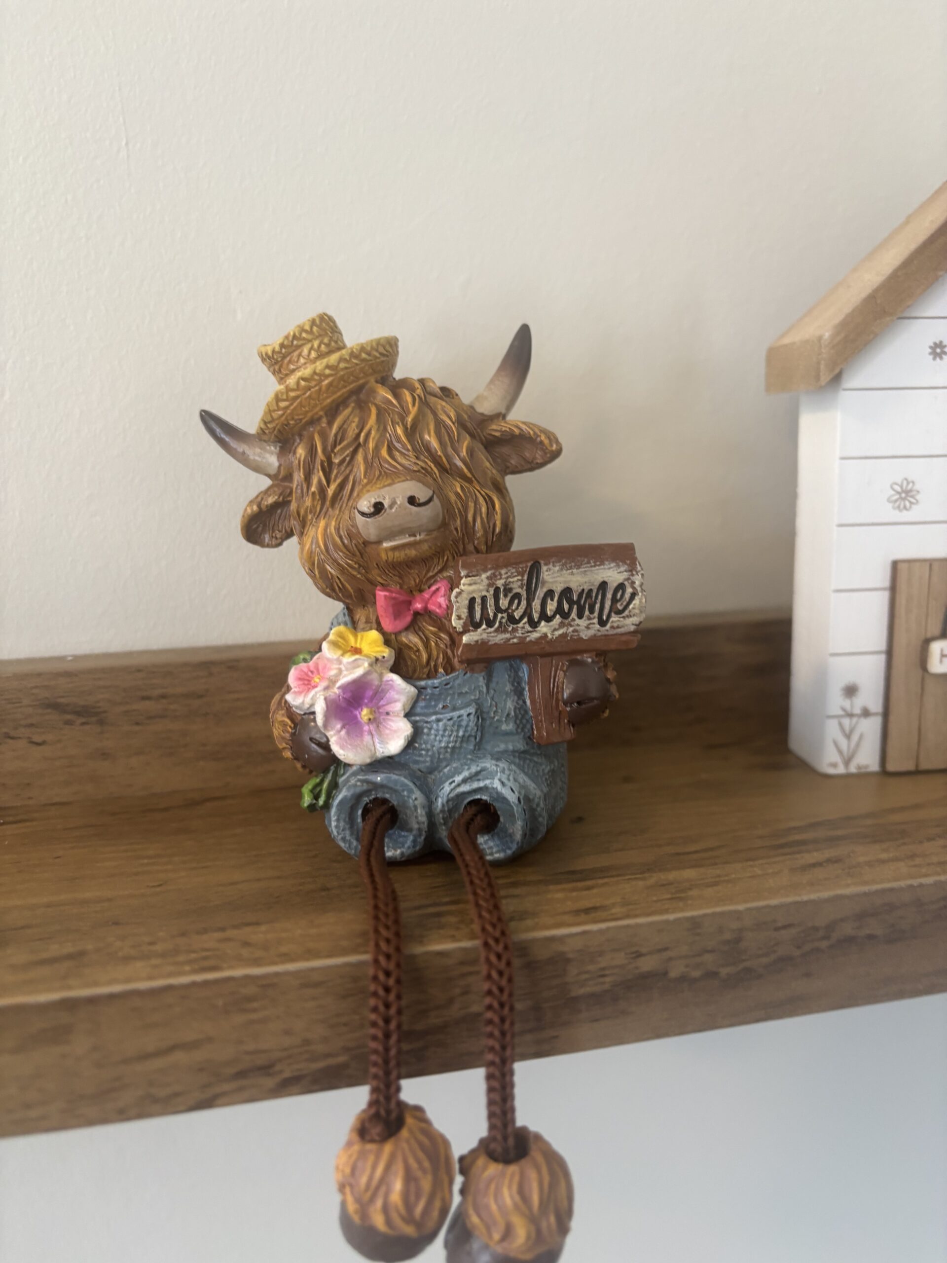 shelf sitting highland cow with welcome sign